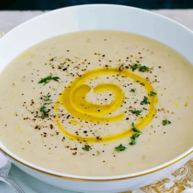 Bowl of creamy potato leek soup garnished with fresh herbs