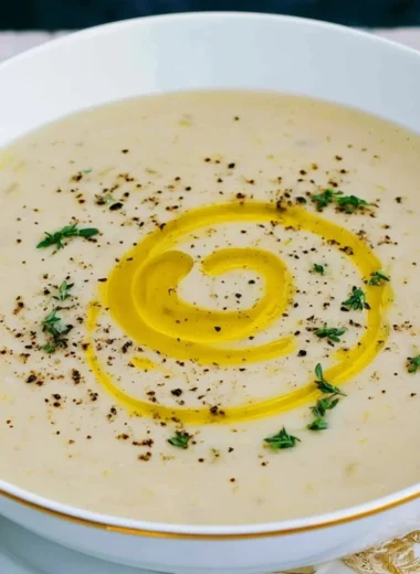 Bowl of creamy potato leek soup garnished with fresh herbs