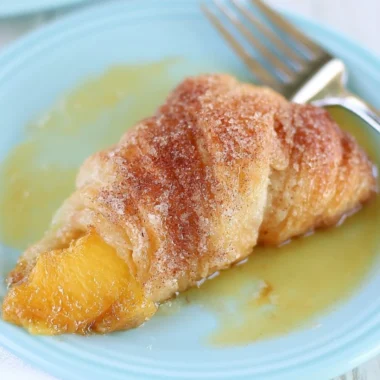 Delicious Peach Cobbler Dumplings served in a bowl with a scoop of vanilla ice cream