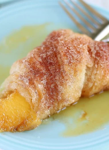 Delicious Peach Cobbler Dumplings served in a bowl with a scoop of vanilla ice cream