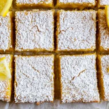 Delicious super easy lemon bars on a wooden table with a lemon slice garnish.
