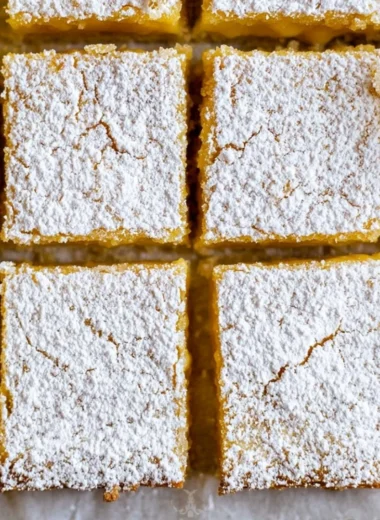 Delicious super easy lemon bars on a wooden table with a lemon slice garnish.